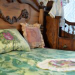 Tradycyjne łóżko z kołdrą i poduszkami w stylu vintage, nadające sypialni charakteru i historii.